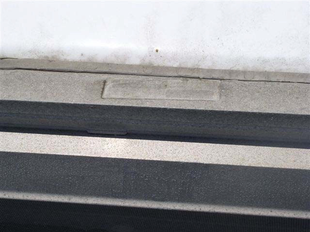 A blank metal placard is affixed to a metal frame that is spotted and worn.