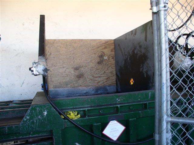 The opening of the green metal bailing machine.
