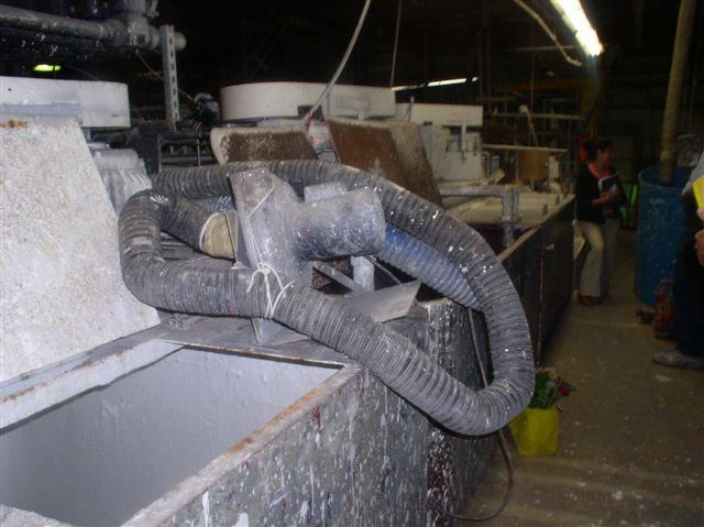 A heavily used, paint-splattered black accordion hose and air filter sits on top of the paint tank.
