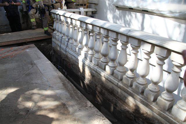 The narrow trench between the concrete patio and a wall of concrete columns.