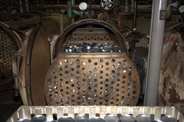 Perforated carts filled with canned tuna being pushed into the retort