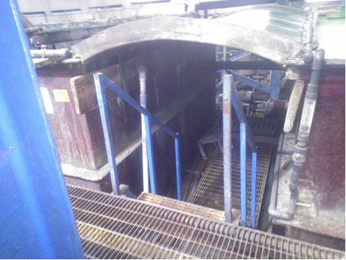 The narrow, tight entrance to the chrome plating tanks between tanks, requiring a person to bend over before descending.