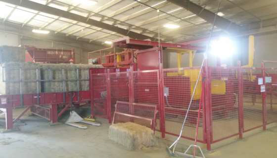 Intake portion of the hay baler showing a stack of hay bales that have come out of the baler.