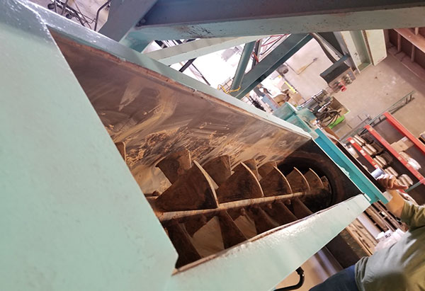 A diagonal view of a long row of blades inside a light green metal casing inside a warehouse.