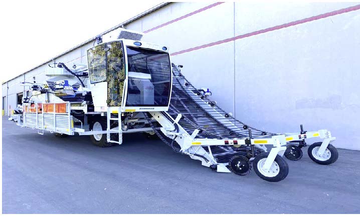A tomato harvester parked outside, next to a building