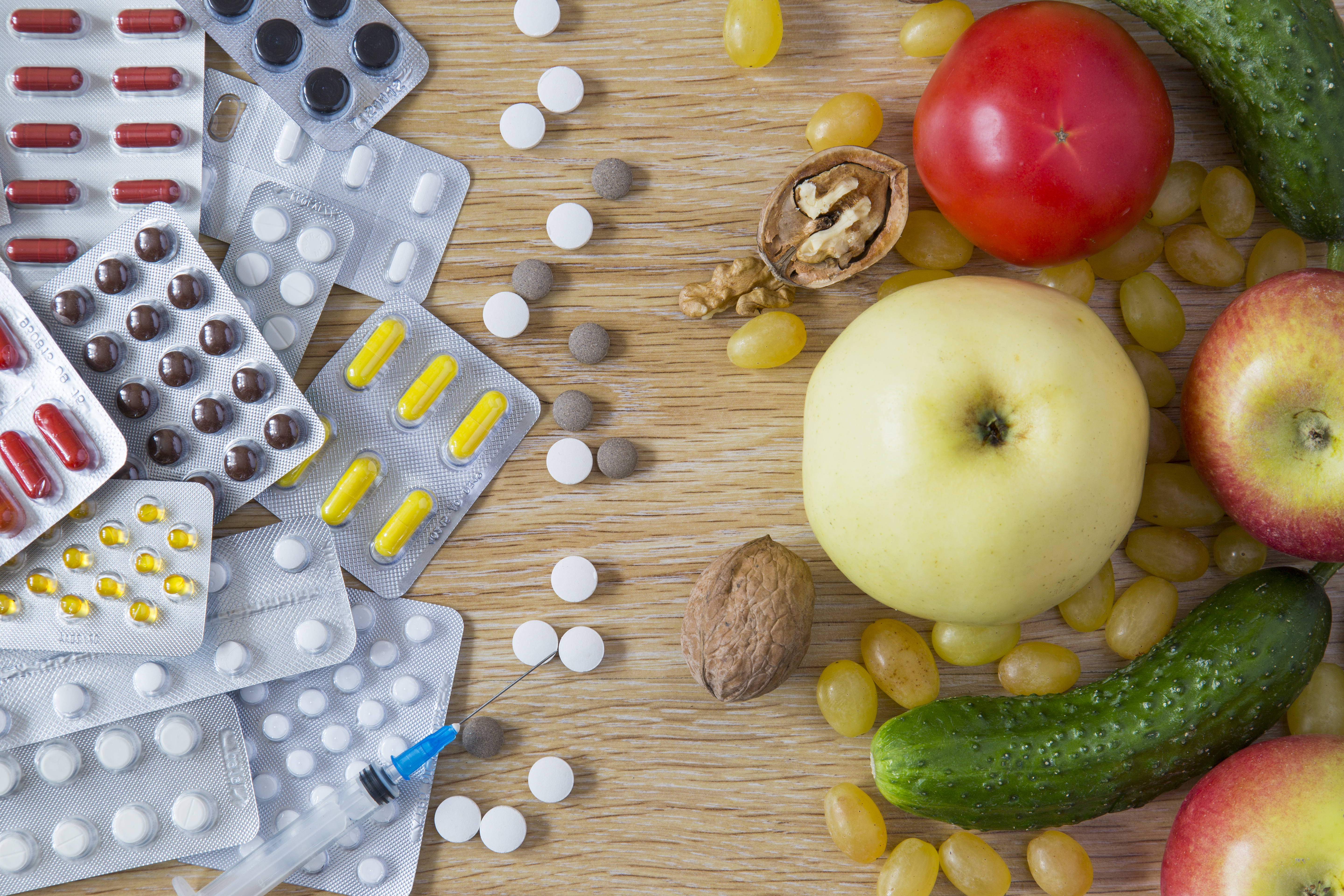 Assortment of medicine, fruits, and nuts scattered on a table