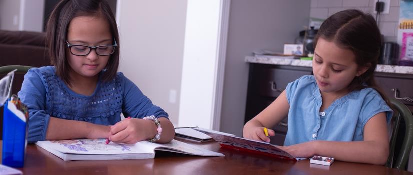 Two Children Sitting at a Table Coloring