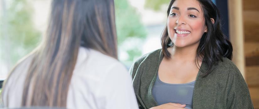 Pregnant Individual Smiles at Provider