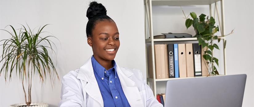 Smiling doctor looks down at her laptop screen
