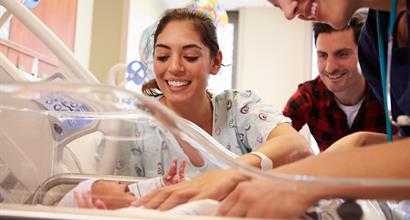 Mother and father visiting her newborn child in maternity ward